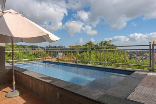a swimming pool with an umbrella on a balcony at Blue Oceana Villa in Nusa Dua
