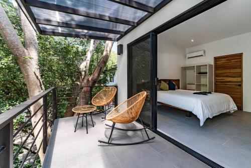 ein Schlafzimmer mit einem Bett und Stühlen auf einem Balkon in der Unterkunft Luxury villa walking distance to Playa Grande in Refundores