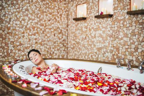 a woman laying in a bath tub covered in confetti at Hotel Jurmala Spa in Jūrmala