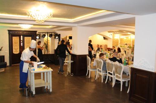 a chef preparing food in a restaurant with a group of people at Aristokrat in Vinnytsya
