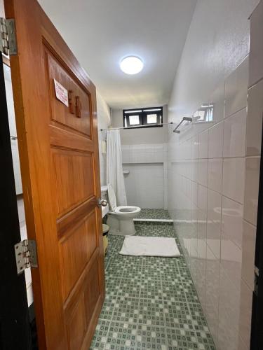 a bathroom with a toilet and a shower and a door at BNK89 Hostel in Bangkok