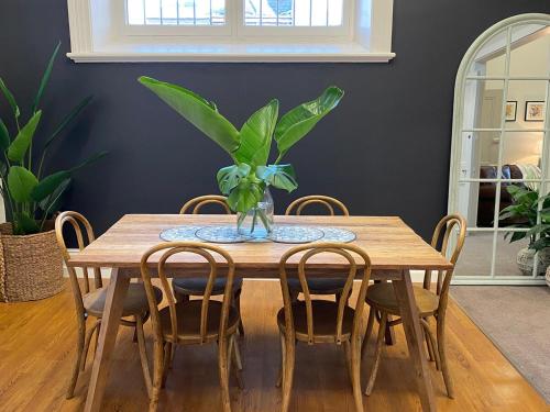 una mesa de madera con sillas y un jarrón con una planta. en Sandhurst View, Bendigo CBD Apartment, en Bendigo