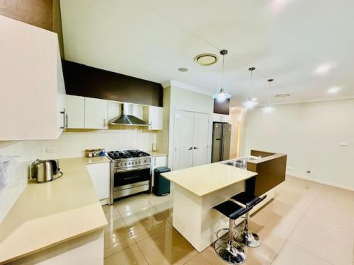 a kitchen with white cabinets and a stove top oven at Entire 4 Bed Rooms Sanctuary in West Hoxton