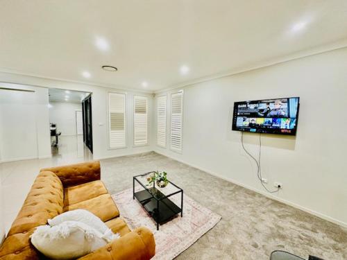 a living room with a couch and a flat screen tv at Entire 4 Bed Rooms Sanctuary in West Hoxton