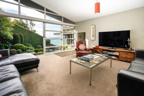 een woonkamer met een bank, een tv en een tafel bij Roseneath Escape - Panoramic Harbour Views in Wellington