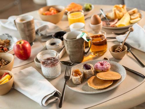 una mesa con una bandeja de alimentos y bebidas para el desayuno en Mövenpick hotel Brussels airport, en Zaventem
