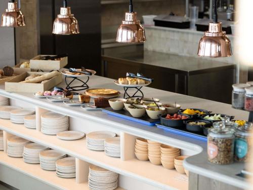 una línea de buffet con platos y comida a la vista en Mövenpick hotel Brussels airport, en Zaventem