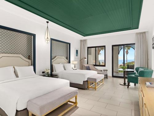 Cette chambre d'hôtel dispose de 2 lits et d'un plafond vert. dans l'établissement Rixos Al Mairid Ras Al Khaimah - Ultra All Inclusive, à Ras al Khaimah