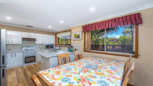 a kitchen and dining room with a table and a window at Gwendolen Cottage - Umina Beach in Ettalong Beach