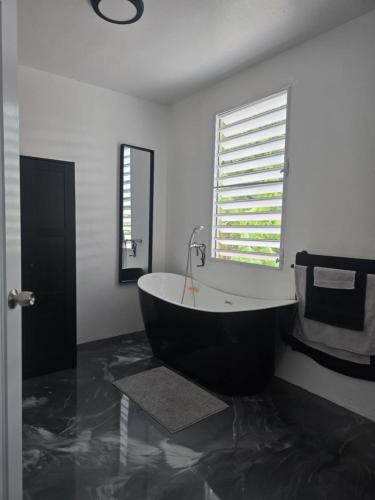 a black and white bathroom with a tub and a window at RiverHouse Luquillo in Ramos