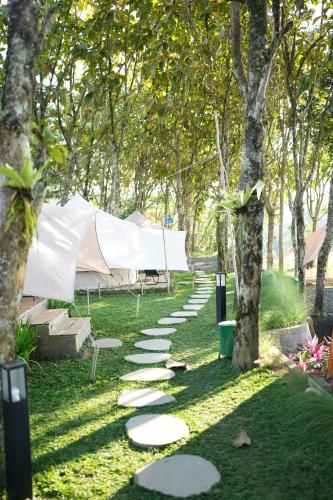 a garden with stepping stones in the grass with a tent at PukuPods - Tent & Cabin in Tabanan