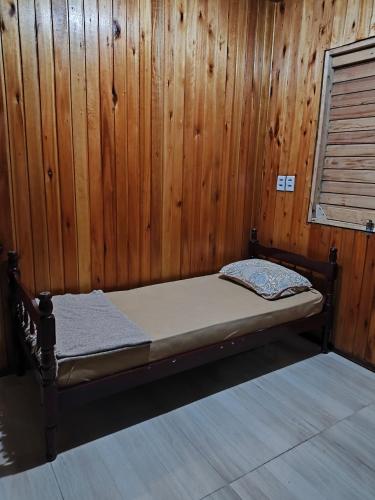 a bed in a room with a wooden wall at Casa de campo da Prof Fabi in Montenegro