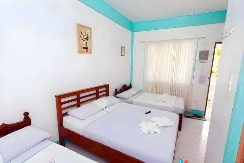 two beds in a room with white walls at Palm Grove Saud Holiday Complex Hotel in Burayoc