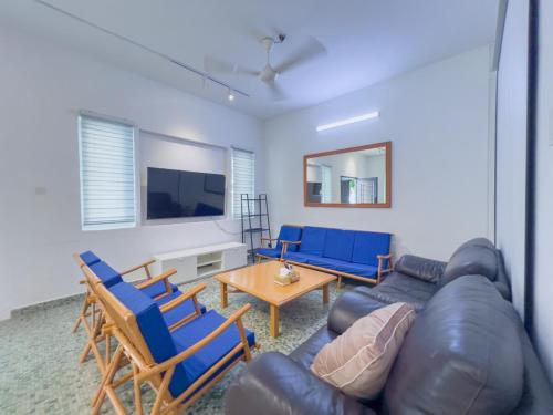 a living room with a leather couch and blue chairs at Tanjung Bungah Holiday Home 4BR 20Pax 6Carpark in Tanjung Bungah