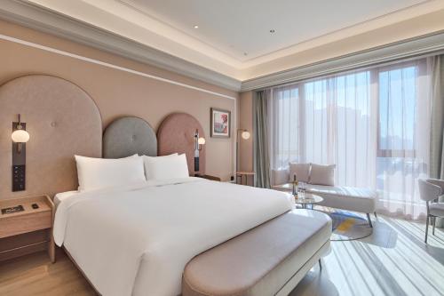 Un dormitorio con una gran cama blanca y una gran ventana. en Mercure Xi'an Chanba, en Xi'an