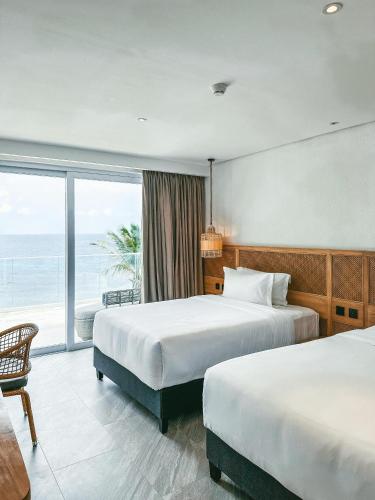 two beds in a hotel room with a view of the ocean at Solea Reef Resort Anda in Anda