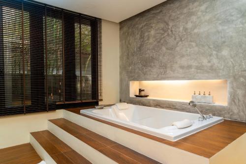 a large bathroom with a tub and a large window at The Anda Mani Khaolak Beachfront Villas in Khao Lak