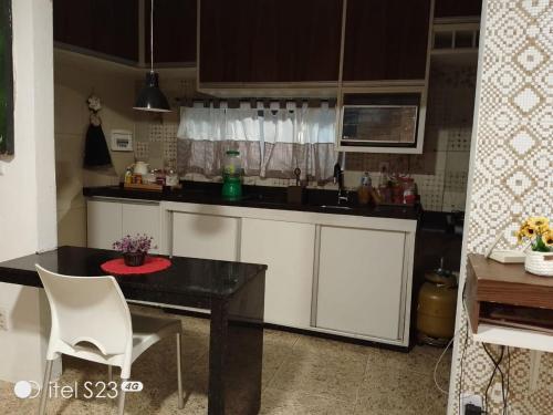 a kitchen with a black table and white cabinets at Casa com piscina e área gourmet em Arembepe in Camaçari