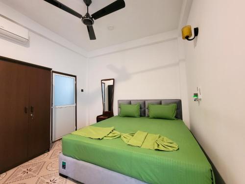 a bedroom with a green bed with a ceiling fan at Sithujaya Green Mirissa in Mirissa