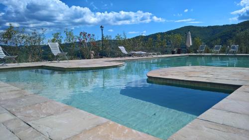 a swimming pool with chairs and mountains in the background at Villa D'Arte Agri Resort in Pontassieve