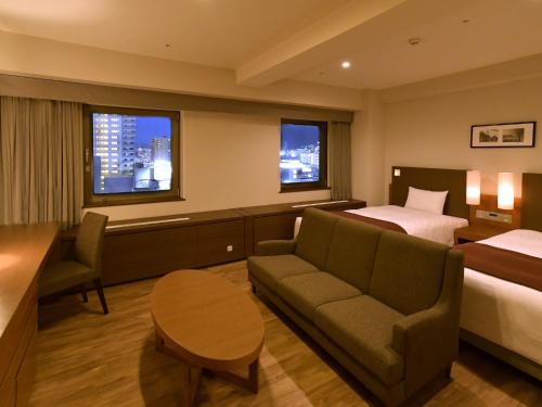 a hotel room with a bed and a couch and a table at Sapporo View Hotel Odori Park in Sapporo