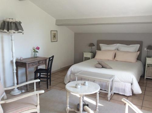 a bedroom with a bed and a table and a desk at Le Clos du Plantis in Sonnac