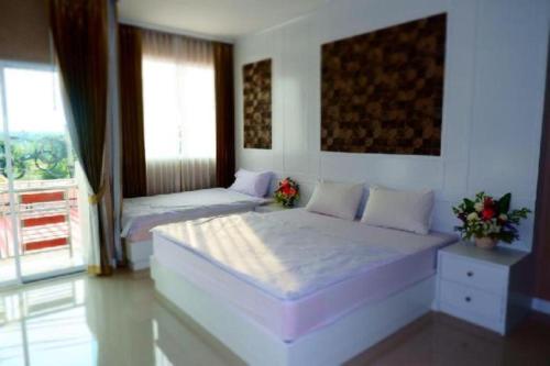 a bedroom with two beds and a large window at Crystal Place Prathai in Prathai