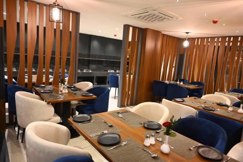 バンガロールにあるGood One Suitesの木製のテーブルと青い椅子のあるレストラン