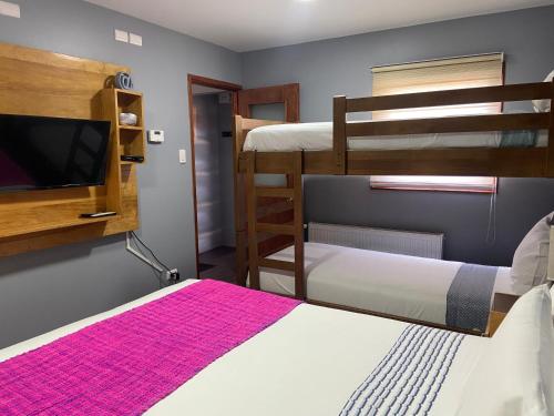 a room with two bunk beds and a flat screen tv at Cabañas Bosque Austral in Punta Arenas
