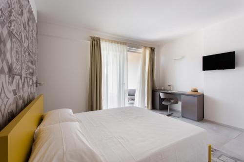a bedroom with a bed and a desk and a television at Luna Minoica Suites and Apartments in Montallegro