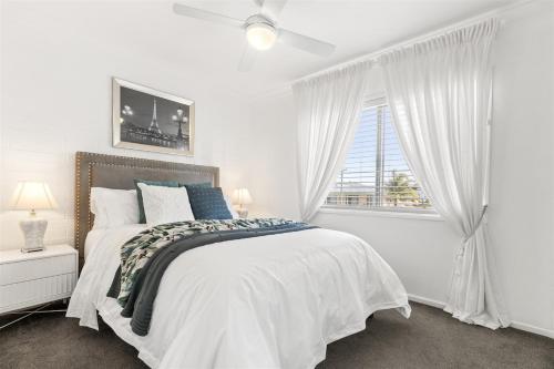 a white bedroom with a bed and a window at Luxury Pool Retreat Ocean & Mountain Views in Scarborough