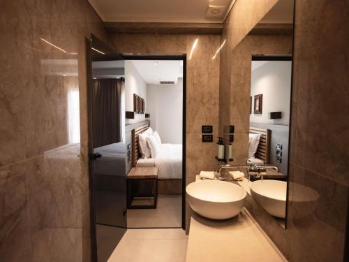 シヴォタにあるMovenpick Resort Agios Nikolaos Sivotaのバスルーム(シンク2台、ベッド1台付)