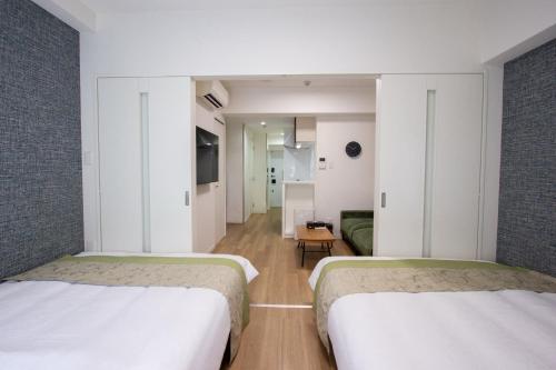 two beds in a hotel room with a hallway at Hotel Ritza HAKATA in Fukuoka