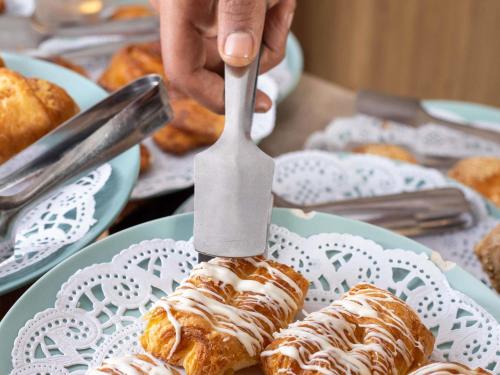a person holding a knife cutting a pastry on a plate at Mövenpick Royal Lotus Nile Cruise, Every Monday Four Nights From Luxor, Every Friday Three Nights From Aswan - Including Excursions & Sightseeing in Luxor