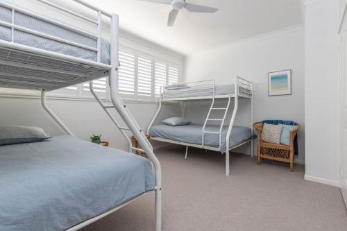 a bedroom with two bunk beds and a chair at Boomerang Bliss in Elizabeth Beach