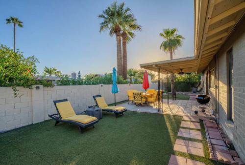 a patio with chairs and umbrellas on the grass at 3bdr Remodeled Scottsdale Desert Pool Oasis and Entertainment in Phoenix