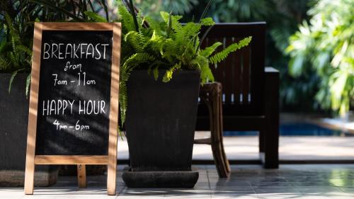 uma placa de giz e um vaso de planta ao lado de uma cadeira em Babel Boutique em Siem Reap