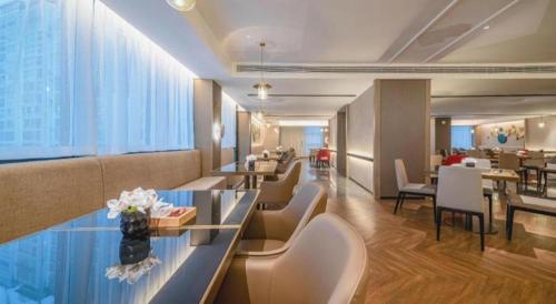a hotel lobby with tables and chairs and a dining room at Echeng Hotel Hezhou Shizheng Square in Wuzhou