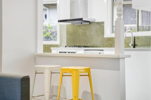a kitchen with two yellow stools in front of a counter at Comfy Croydon Family Getaway Near Trails and Cafes in Ringwood North