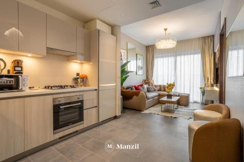 a kitchen and a living room with a couch at Manzil - Luxury 1BR in Sobha Hartland w Pool & Gym Access in Dubai