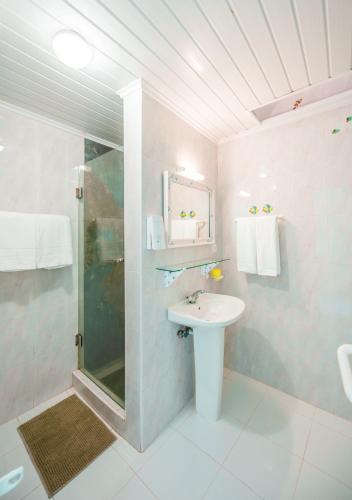 a white bathroom with a shower and a sink at Casa do Cais in Calheta