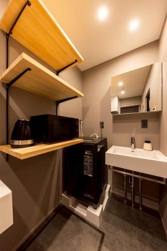a small kitchen with a sink and a microwave at STAY THE RINKU BAY Apartment Hotel in Izumi-Sano