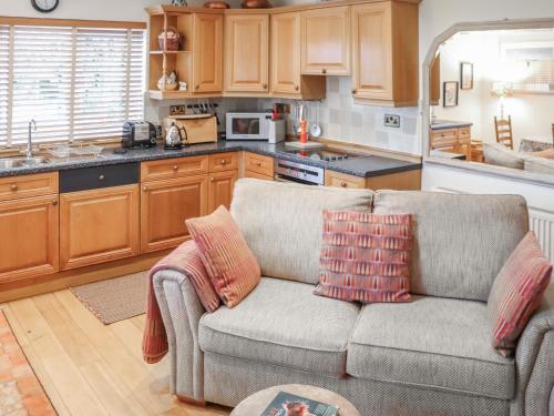 a living room with a couch and a kitchen at Snowdrop Cottage in Treffynnon 
