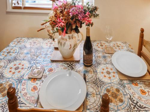 a table with plates and a vase with flowers on it at Snowdrop Cottage in Treffynnon 