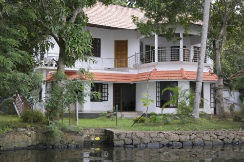 a white house with a river in front of it at Lovedale Lakeside Homestay in Alleppey