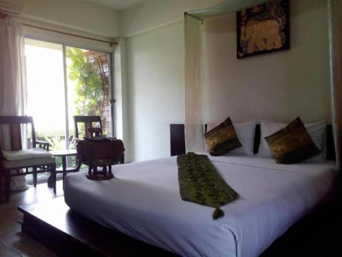 Un dormitorio con una gran cama blanca y una ventana. en Baan Pim, en Chiang Mai