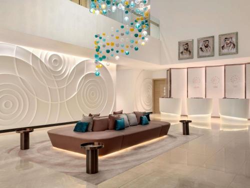 a living room with a couch and a chandelier at Novotel Dubai Gold District in Dubai