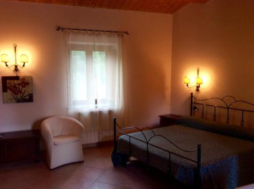 a bedroom with a bed and a chair and a window at Masseria degli Alberti in Mormanno
