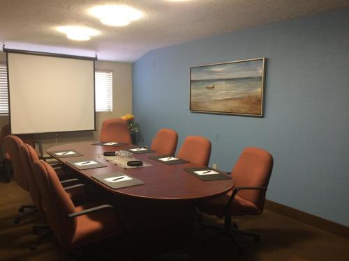 a conference room with a table and chairs and a screen at Coastal Inn Moncton/ Dieppe in Moncton