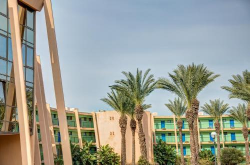 a row of palm trees in front of a building at Alma in Caesarea